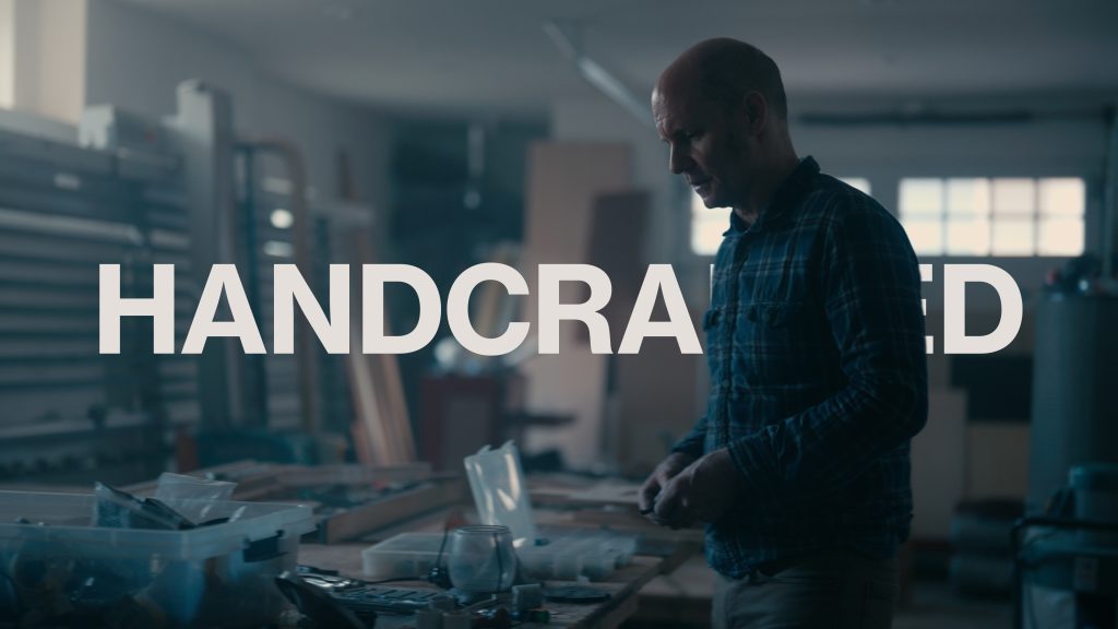 Man restoring salvaged materials at a work bench. Image links to a page where the short documentary Handcrafted can be watched.