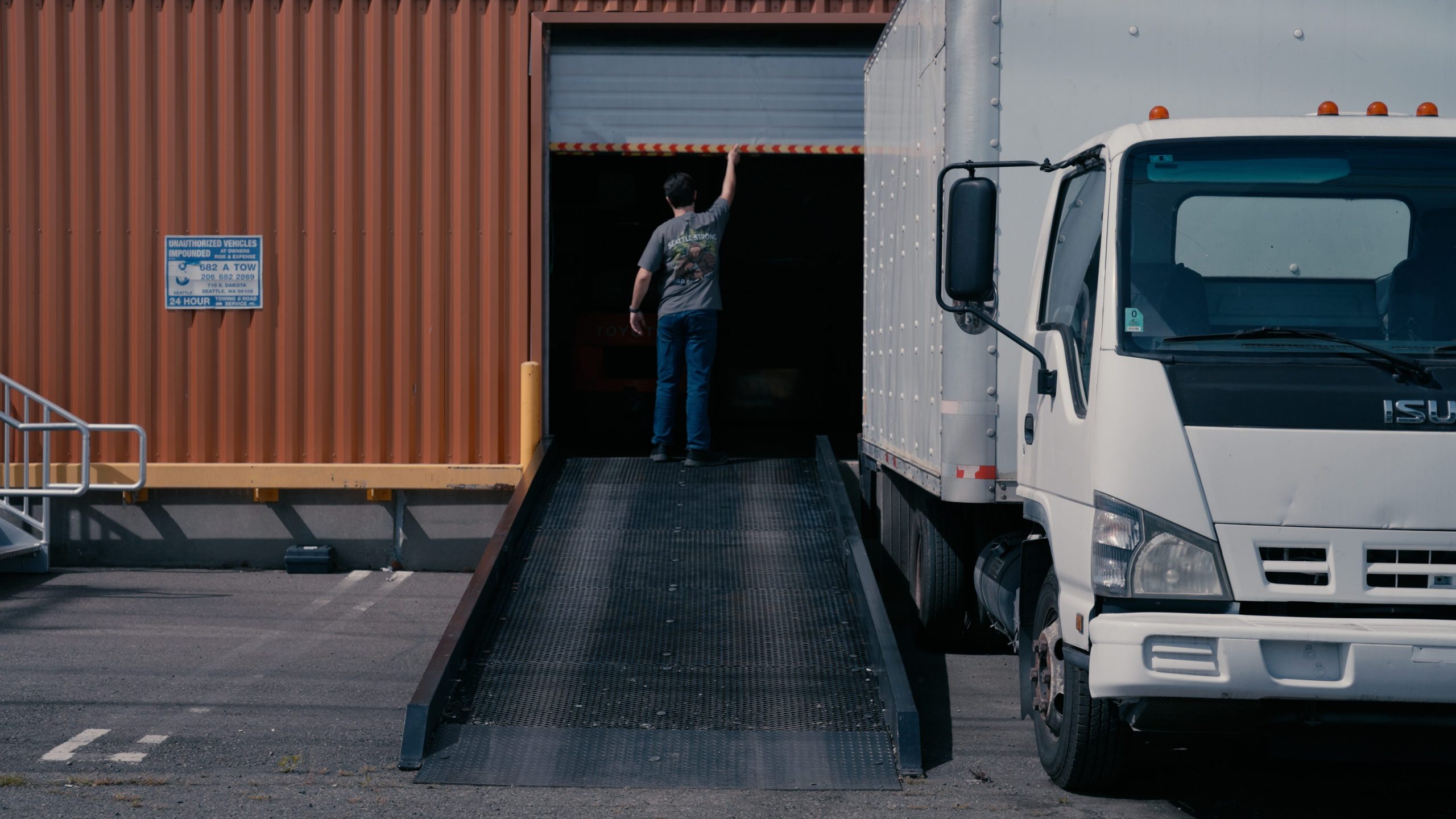 Man opening an industrial warehouse garage door. Image links to a video campaign produced for Seattle Strong Coffee Co.