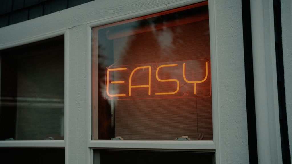 Neon sign hanging in window that says "EASY"