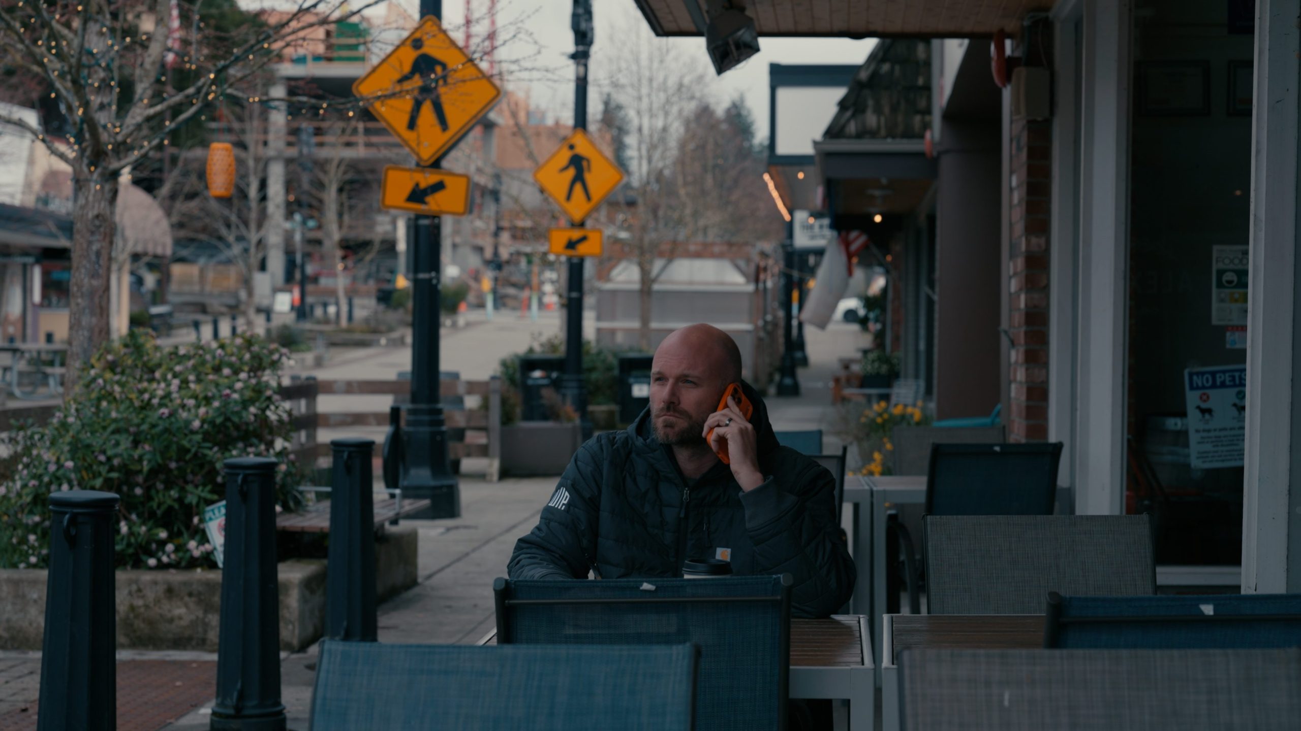 Man sitting at table on cell phone. Image links to a video campaign produced for the Bothell Kenmore Chamber of Commerce.